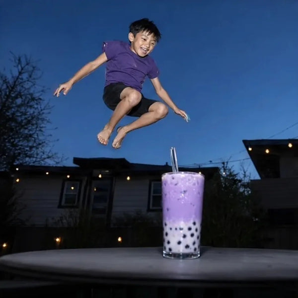 Boy jumping on a trampoline over a taro boba