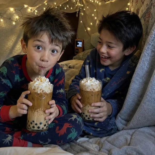 Brothers in pajamas with whipped cream boba in a blanket fort