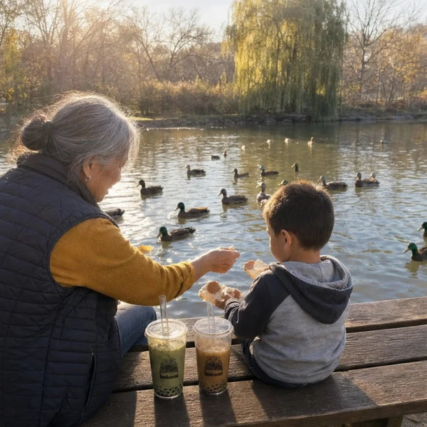 Grandma and grandson feeding ducks by the pond with two Boboza cups