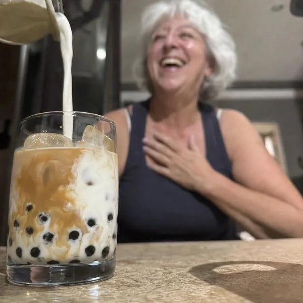 Grandma laughing while milk pours into an iced boba glass