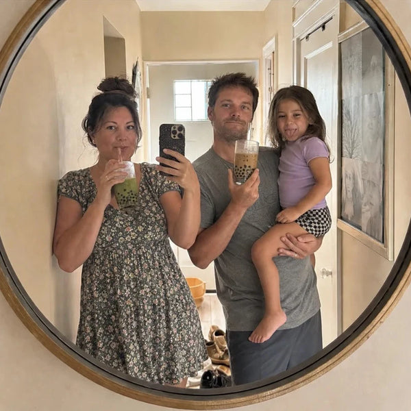 Family mirror selfie with boba drinks in a round hallway mirror
